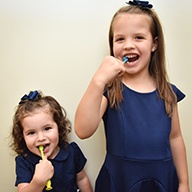 Dentist smiling with two younger dental patients