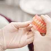 White gloved hands holding a full set of dentures