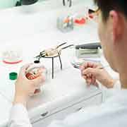 Lab tech carving a set of dentures on a mold