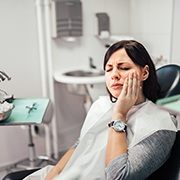 Woman with tooth pain sitting in dental chair