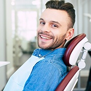 Man in denim jacket smiling in dental chair