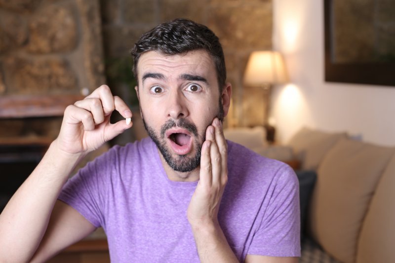 A surprised young man holding a missing tooth